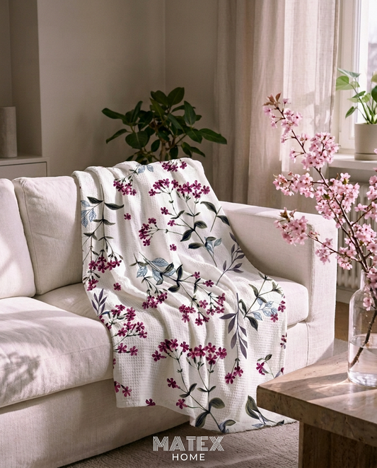 Cherry Bloom Pique Blanket draped on a sofa